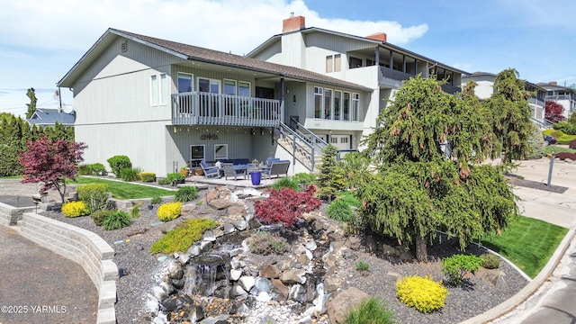 back of property featuring stairs, a chimney, and a patio