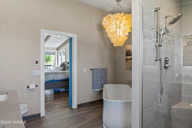 bathroom featuring a notable chandelier, a tile shower, wood finished floors, and ensuite bathroom