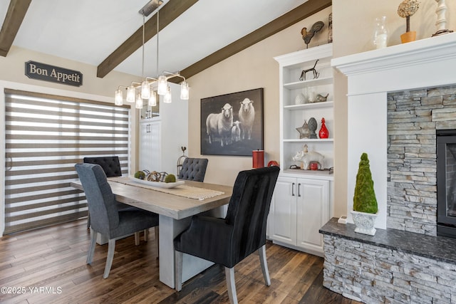 dining area with dark wood-type flooring, lofted ceiling with beams, built in shelves, and a fireplace
