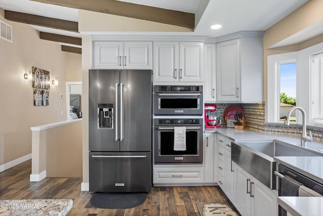 kitchen with a sink, decorative backsplash, dark wood finished floors, and stainless steel appliances
