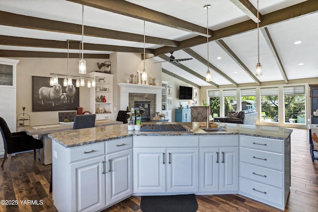 kitchen featuring white cabinets, dark wood-style flooring, light stone counters, open floor plan, and stainless steel gas stovetop