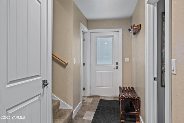entryway with baseboards, a textured wall, and stairway