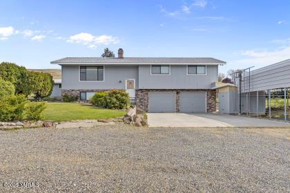 split foyer home with stone siding, driveway, and a garage