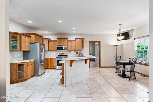 9307 Torrey Pines Ln, Yakima, WA 98908 - kitchen featuring stainless steel appliances, a kitchen bar, brown cabinetry, light countertops, and recessed lighting