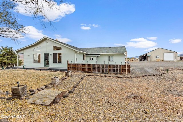 back of property featuring a detached garage, a deck, and an outdoor structure