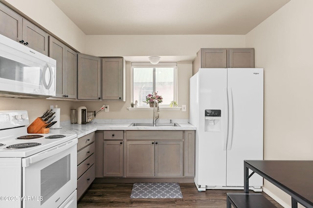 kitchen featuring dark wood-style floors, white appliances, light countertops, and a sink