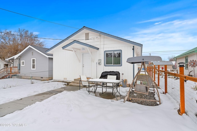 snow covered back of property featuring crawl space and fence