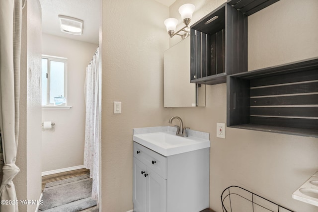 full bath featuring baseboards and vanity