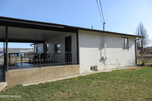 view of home's exterior featuring concrete block siding, a lawn, and a carport