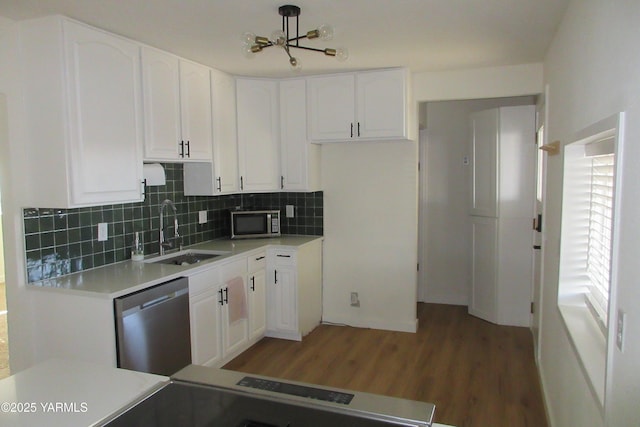 kitchen with a sink, white cabinets, tasteful backsplash, and stainless steel appliances