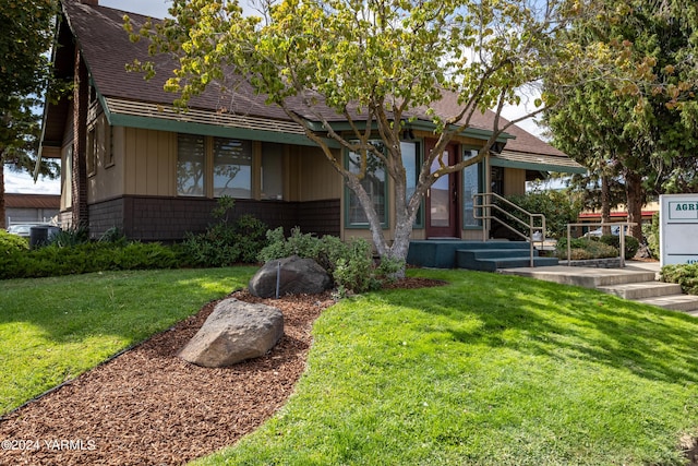 view of front of property with brick siding, roof with shingles, and a front yard