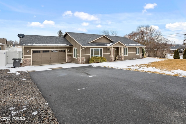 view of front facade featuring driveway, stone siding, roof with shingles, an attached garage, and board and batten siding