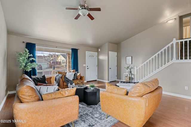 living room featuring baseboards, ceiling fan, stairs, vaulted ceiling, and wood finished floors