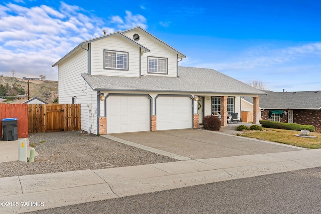 traditional home with fence, a porch, a shingled roof, concrete driveway, and a garage