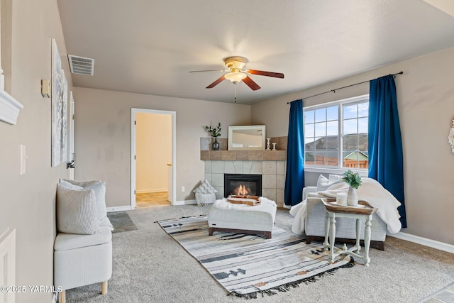 living room featuring visible vents, baseboards, a ceiling fan, and a tile fireplace