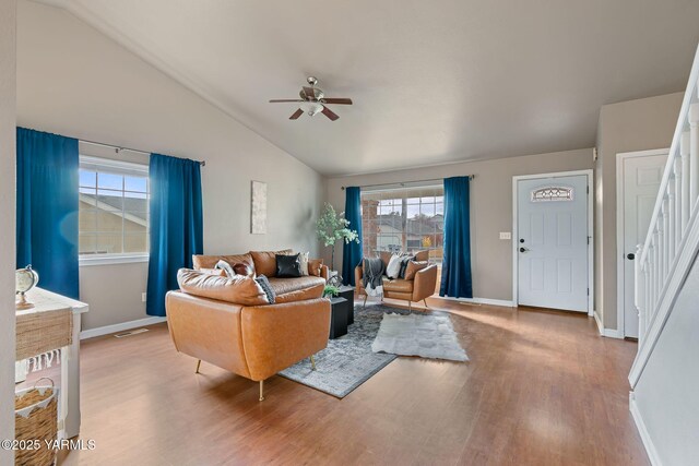 living area featuring wood finished floors, stairway, baseboards, lofted ceiling, and ceiling fan