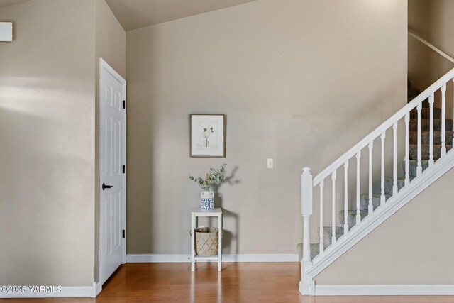 entryway with stairway, wood finished floors, and baseboards