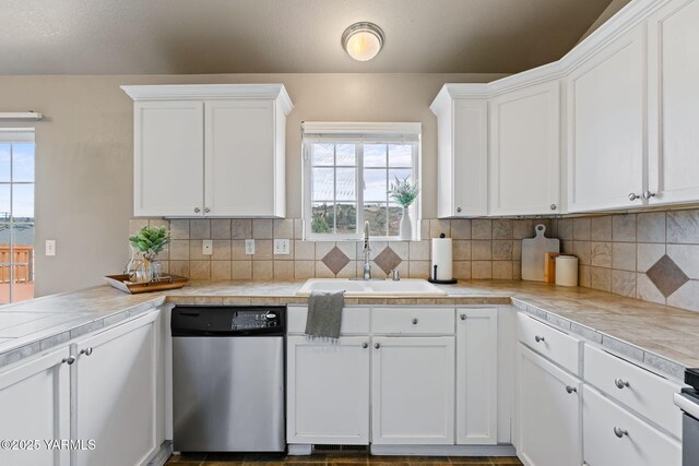 kitchen featuring a sink, tasteful backsplash, dishwasher, and white cabinetry