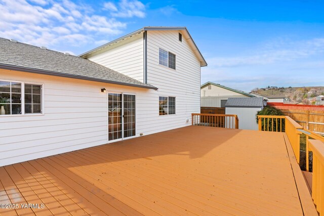 deck with an outbuilding, a storage shed, and fence