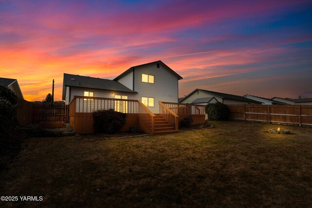 back of house with a deck, a lawn, and a fenced backyard