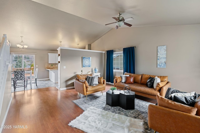 living room with lofted ceiling, light wood-style flooring, ceiling fan with notable chandelier, and baseboards