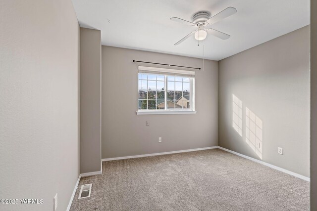 carpeted spare room with visible vents, baseboards, and ceiling fan