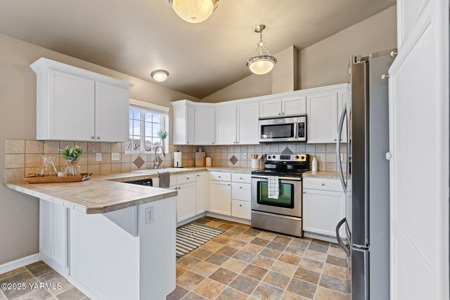 kitchen featuring a peninsula, light countertops, white cabinets, appliances with stainless steel finishes, and backsplash