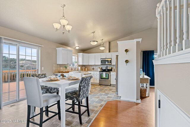 dining space featuring a notable chandelier and vaulted ceiling