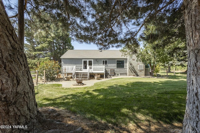rear view of property featuring a deck, a lawn, and fence