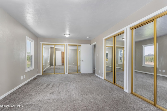 unfurnished bedroom featuring multiple closets, carpet floors, and baseboards
