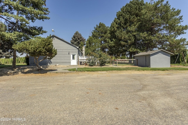 view of side of home with an outbuilding, fence, and a storage shed