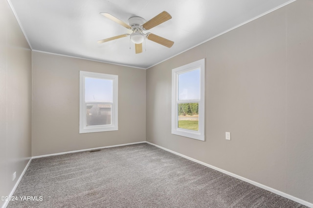 carpeted empty room with ornamental molding, visible vents, ceiling fan, and baseboards