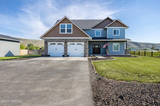 craftsman inspired home featuring aphalt driveway, a front yard, fence, and a mountain view