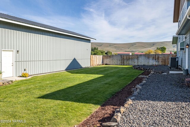 view of yard featuring a fenced backyard, a mountain view, and cooling unit