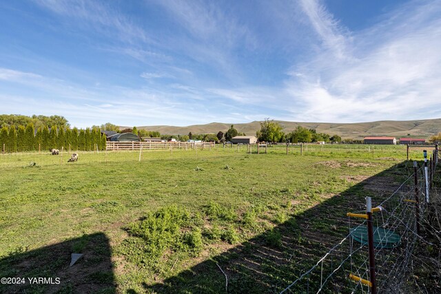 view of yard with a rural view, a mountain view, and fence