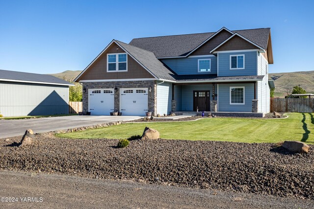 craftsman inspired home with an attached garage, a mountain view, fence, driveway, and a front yard