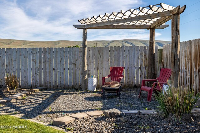 view of yard with a fenced backyard, a fire pit, a mountain view, and a pergola