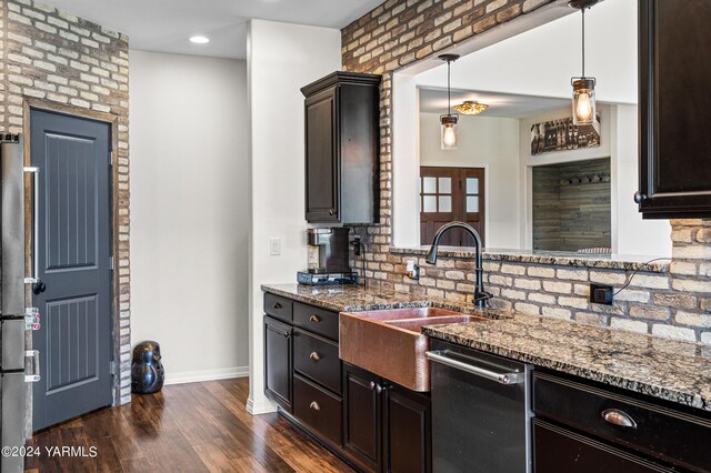 kitchen with dark wood-style flooring, a sink, hanging light fixtures, stainless steel dishwasher, and dark stone countertops