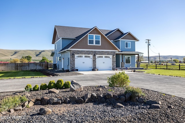 craftsman inspired home with a front yard, a mountain view, driveway, and fence