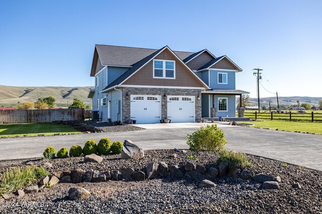 craftsman inspired home with a front yard, a mountain view, driveway, and fence