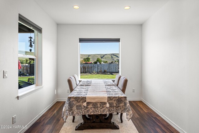 dining space with dark wood-type flooring, a mountain view, and baseboards