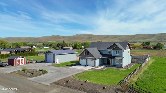 view of front of house featuring a mountain view, a garage, fence, driveway, and a front lawn