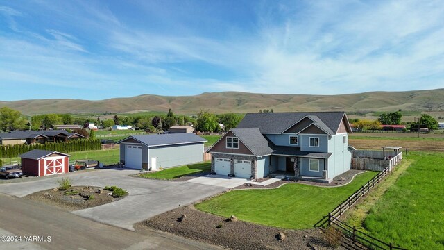 view of front of house featuring a mountain view, a garage, fence, driveway, and a front lawn