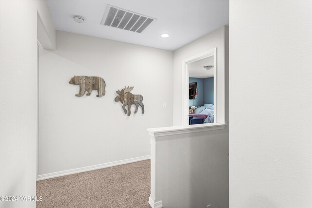 hallway featuring baseboards, visible vents, and carpet flooring