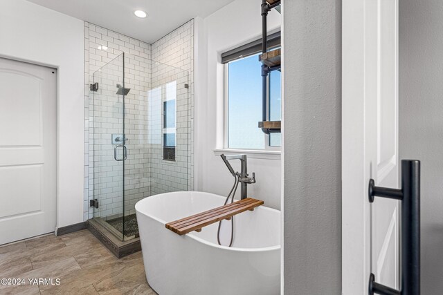 bathroom with a shower stall, a freestanding bath, and recessed lighting