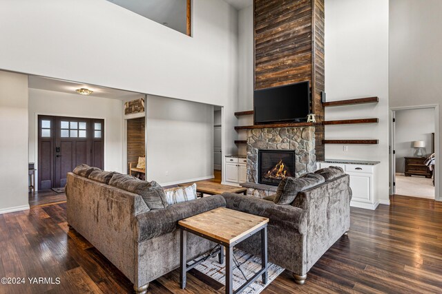 living area featuring baseboards, a fireplace, a high ceiling, and dark wood-type flooring