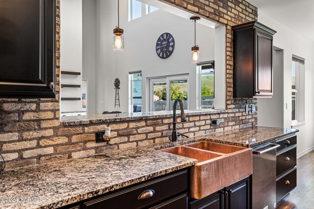 kitchen with stone counters, a sink, dark wood-style floors, decorative light fixtures, and dishwasher