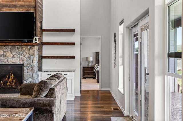 foyer with dark wood-style floors, a fireplace, a towering ceiling, and baseboards