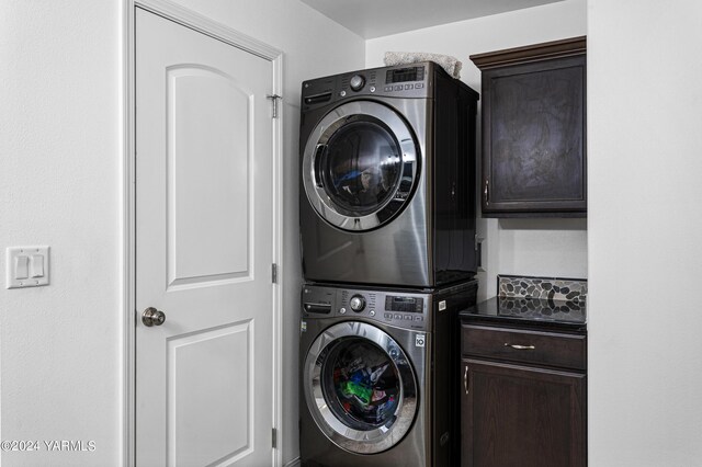 clothes washing area with cabinet space and stacked washer and dryer