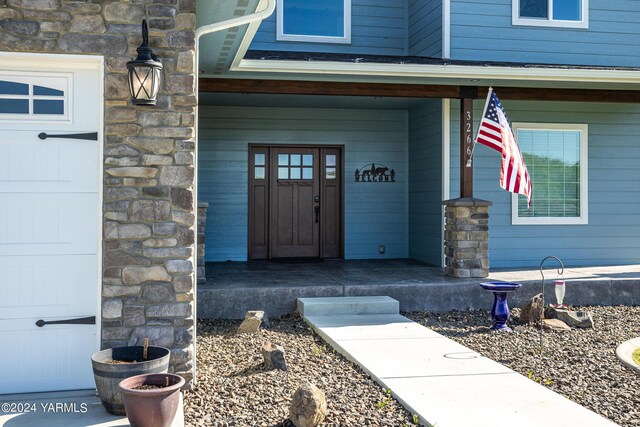 view of exterior entry featuring a garage and a porch